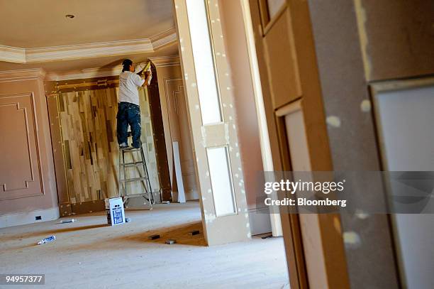 Juan Contreras caulks a wall in preparation for painting a new home in Alpharetta, Georgia, U.S., on Friday, March 20, 2009. The deepening economic...