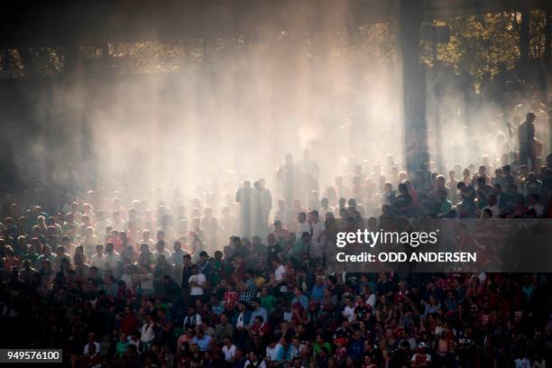 The sun cuts through the haze of flares hanging in the stand during the German first division Bundesliga football match between Hannover 96 vs Bayern...