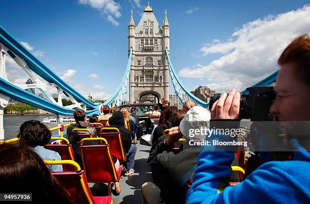 Tourist takes a photo from an open top bus as it passes Tower Bridge during a bus tour in London, U.K., on Thursday, May 21, 2009. Tourism is...