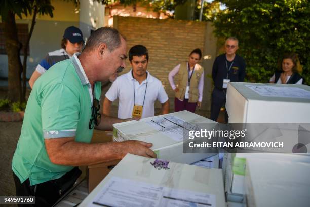 Election observers from the European Union and the Organization of American States look at workers downloading voting material at a polling station...