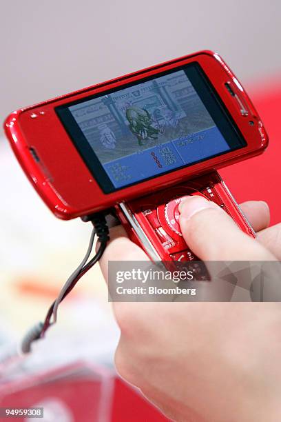 Visitor uses a NTT DoCoMo Inc.'s mobile phone to play a video game during a media preview at the Tokyo Game Show 2009 in Chiba City, Japan, on...