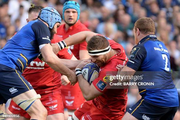 Scarlets' Lewis Rawlins is tackled by Leinster's Australian flanker Scott Fardy and Leinster's Irish hooker Sean Cronin during the European Champions...