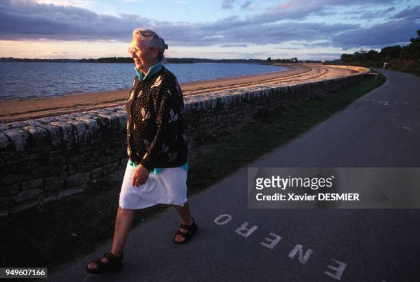 Femme âgée se promenant au bord de la plage de l'Ile d'Arz, dans le Morbihan, France.