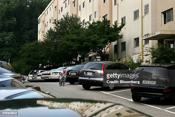 An elderly woman walks through the parking lot at the Gaepo-dong apartment complex in Seoul, South Korea, on Wednesday, July 15, 2009. South Korea's...