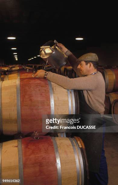 Ouillage du vin dans une cave du domaine viticole de Château Latour, à Pauillac, en Gironde, France.