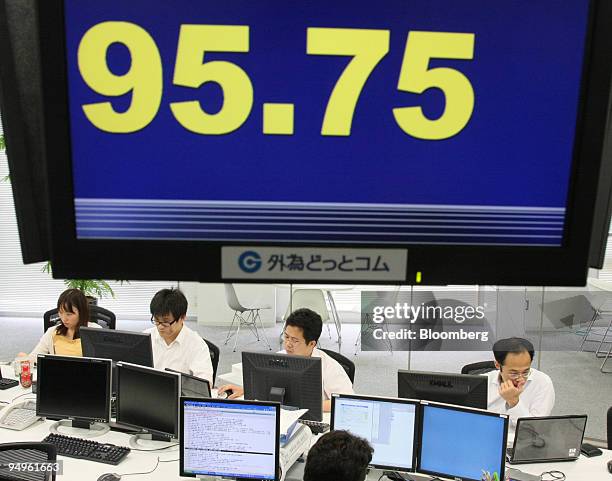 Dealers work under an electronic board displaying the current value of the yen against the U.S. Dollar at a foreign exchange brokerage in Tokyo,...