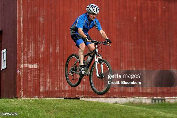 Cyclist is airborne while riding past a barn on the Kingdom Trails in East Burke, Vermont, U.S., on Wednesday, June 17, 2009. Kingdom Trails features...