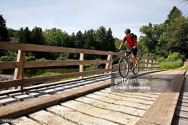 Cyclist rides on a bridge that spans a river on the Kingdom Trails in East Burke, Vermont, U.S., on Wednesday, June 17, 2009. Kingdom Trails features...