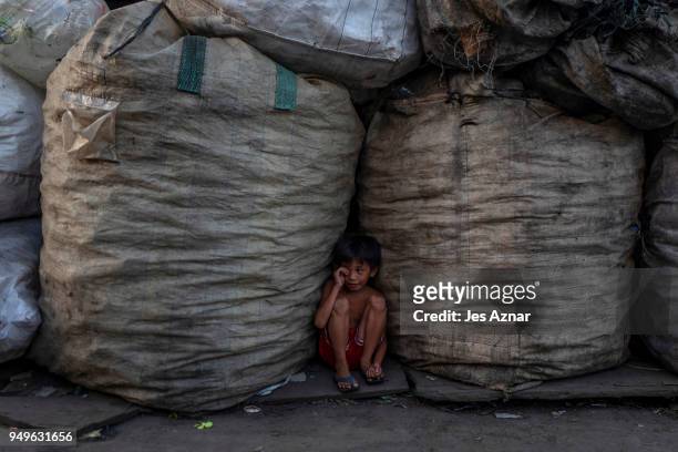 Boy sitting between sacks of collected plastics on April 18, 2018 in Manila, Philippines. The Philippines has been ranked third on the list of the...
