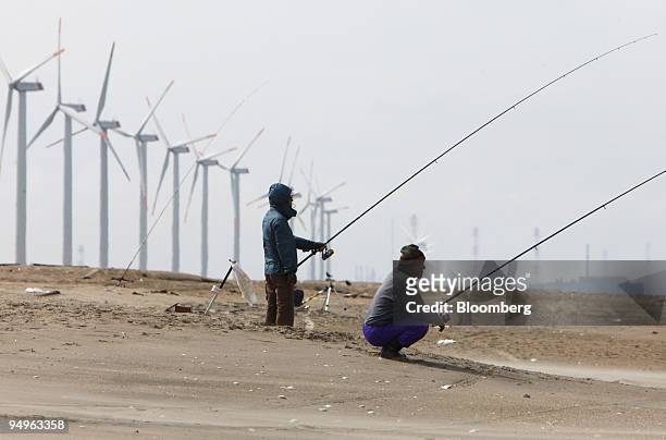 Men fish in front of wind turbines at the Hasaki Wind Farm in Kamisu City, Ibaraki Prefecture, Japan, on Tuesday, July 7, 2009. Prime Minister Taro...