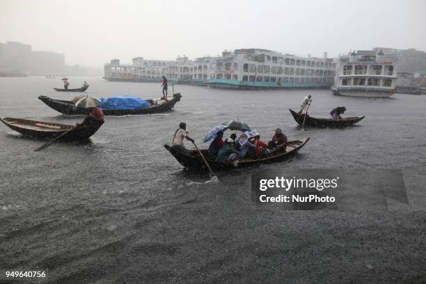 Residents cross over the Buriganga River by wooden boat in Dhaka during the heavy rain fall as the pre-monsoon rains begin in Bangladesh on April 21,...