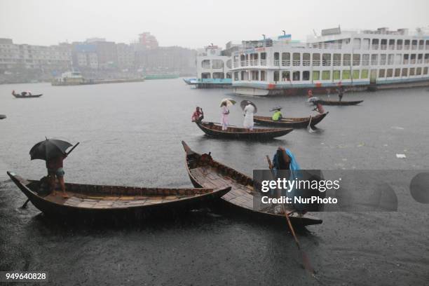 Residents cross over the Buriganga River by wooden boat in Dhaka during the heavy rain fall as the pre-monsoon rains begin in Bangladesh on April 21,...