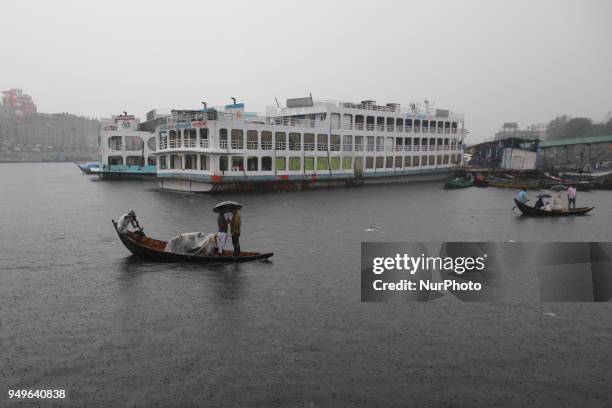 Residents cross over the Buriganga River by wooden boat in Dhaka during the heavy rain fall as the pre-monsoon rains begin in Bangladesh on April 21,...