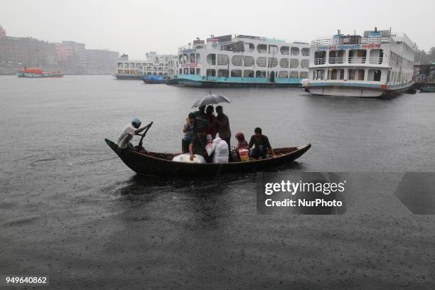 Residents cross over the Buriganga River by wooden boat in Dhaka during the heavy rain fall as the pre-monsoon rains begin in Bangladesh on April 21,...
