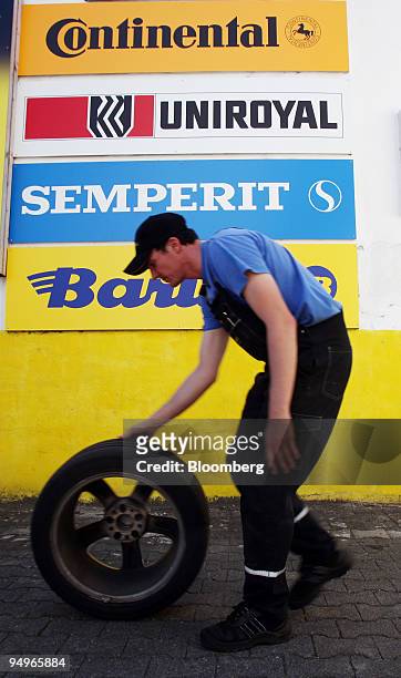 Mechanic Thorsten Metzger rolls a Continental tire in a garage in Frankfurt, Germany, on Monday, July 27, 2009. Continental AG, the German car-parts...