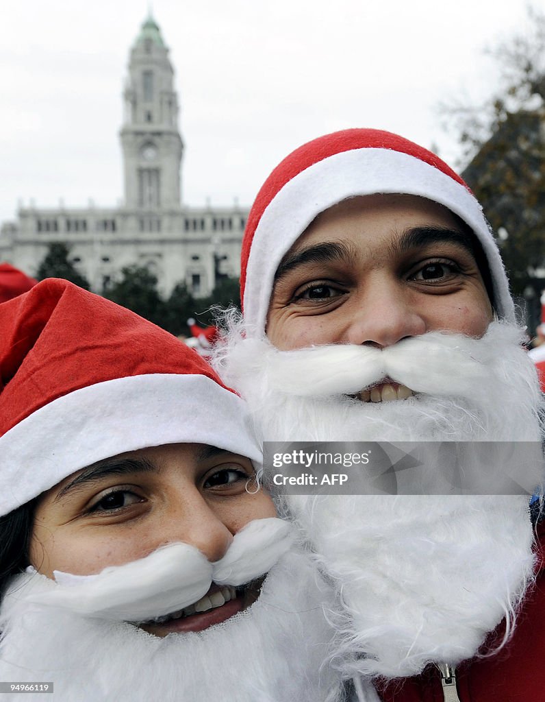 A  couple dressed as Santa Claus pose fo