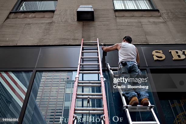 Bobby Gonzalez pre-drills holes as he hangs a sign outside a Brooks Brothers store in New York, U.S., on Wednesday, Aug. 5, 2009. U.S. Service...