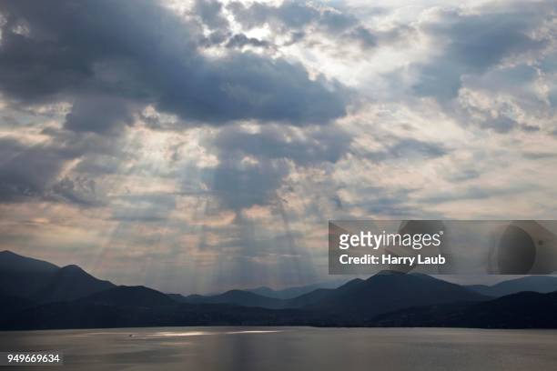 dramatic cloud formation, sunbeams behind dark clouds, thunderstorm atmosphere, lago maggiore, verbano-cusio-ossola province, piedmont region, italy - province of verbano cusio ossola stock pictures, royalty-free photos & images
