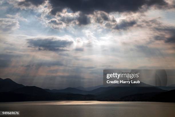 dramatic cloud formation, sunbeams behind dark clouds, thunderstorm atmosphere, lago maggiore, verbano-cusio-ossola province, piedmont region, italy - province of verbano cusio ossola fotografías e imágenes de stock