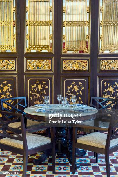 Dining table in front of a Straits Chinese gold leaf screen at Kebaya Restaurant at Seven Terraces Hotel in George Town, Penang, Malaysia.