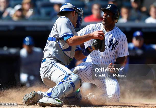 Miguel Andujar of the New York Yankees scores a run against Luke Maile of the Toronto Blue Jays after a sacrifice fly in the sixth inning at Yankee...