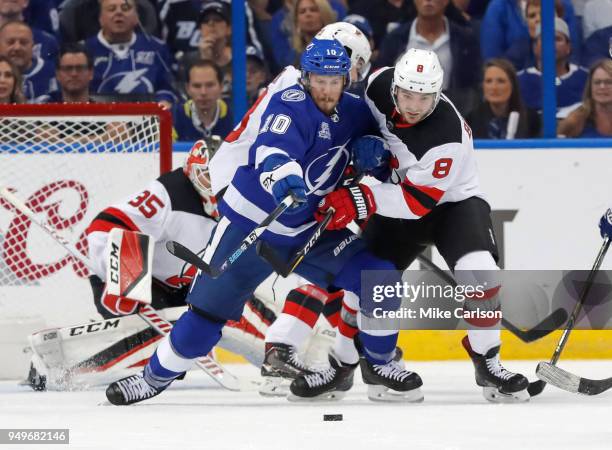 Miller of the Tampa Bay Lightning battles with Will Butcher of the New Jersey Devils for a loose puck in front of Cory Schneider in the first period...