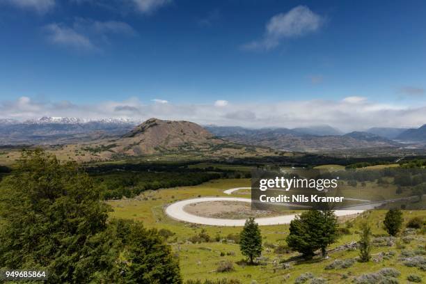 curvy road carretera austral leads through green hillside, behind andes, near coyhaique, region de aysen, chile - carretera stock-fotos und bilder