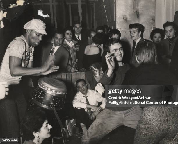 Woman and man dance to the accompaniment of a drummer beating on congas, at a party in Greenwich Village, ca.1956.