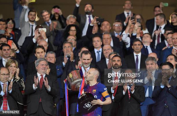 Spain's king Felipe VI handles the trophy to Barcelona's Spanish midfielder Andres Iniesta after the Spanish Copa del Rey final football match...