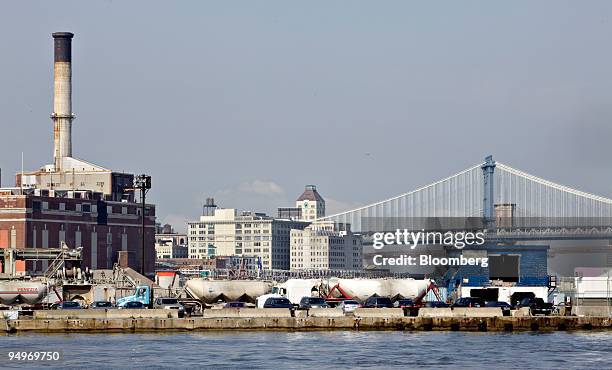 The Manhattan bridge, right, stands beyond cement trucks outside a factory as seen from the Red Hook neighborhood of Brooklyn, New York, U.S., on...
