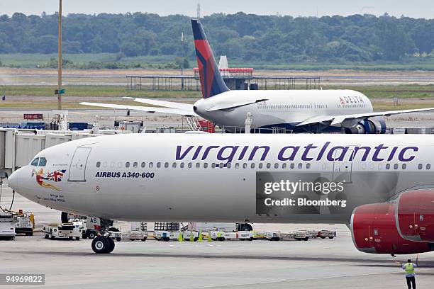 Virgin Atlantic plane taxis past a Delta plane at John F. Kennedy International Airport in New York, U.S., on Monday, July 20, 2009. Virgin Atlantic...