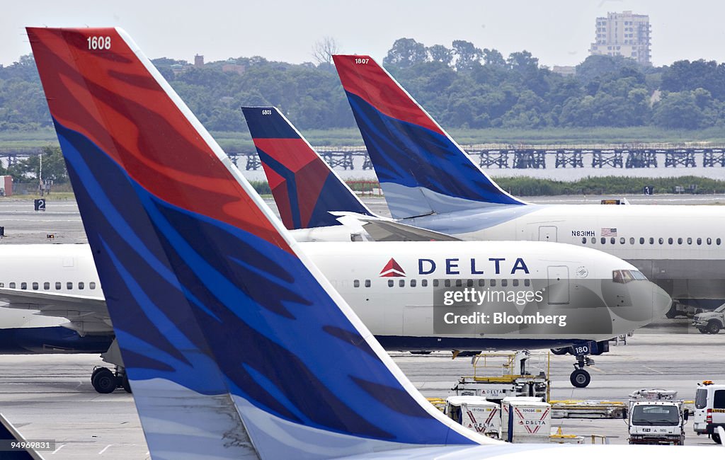 A Delta Air Lines plane taxis toward a gate between other De