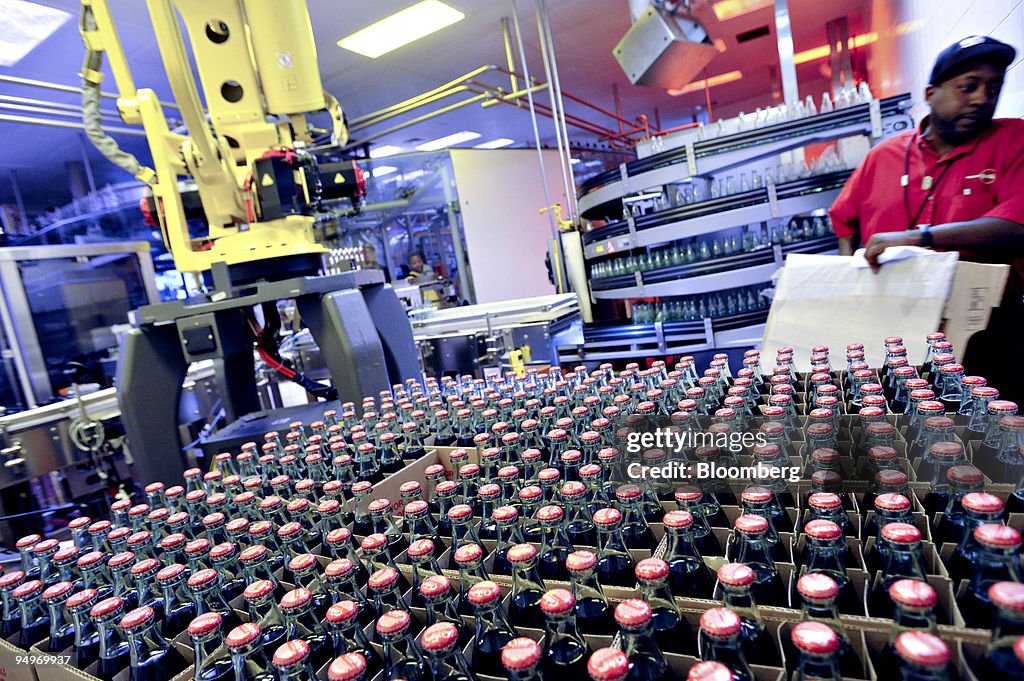 Bottles of Coca-Cola sit in boxes inside the bottling area a