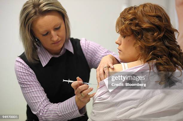 Year-old Chloe Gibbons, a call center worker, right, looks away as Luiza Duszynski, a nursing supervisor at the Royal Adelaide Hospital, injects her...