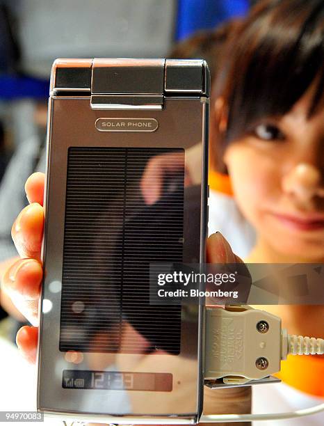 Model shows off the "Solar Phone," solar power charging mobile phone manufactured by Sharp Corp., at the KDDI Corp. Booth at the Wireless Japan 2009...