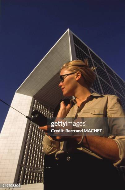 Employée téléphonant au pied de la Grande Arche de la Fraternité, dans le quartier de la Défense à Puteaux, dans les Hauts-de-Seine, France.