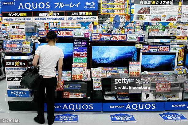 Customer looks at Sharp Corp. "Aquos" liquid-crystal display televisions at an electronics store in Tokyo, Japan, on Thursday, July 30, 2009. Sharp...