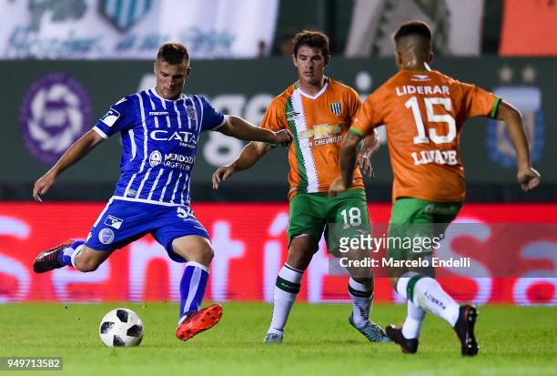 Leandro Lencinas of Godoy Cruz kicks the ball against Mauricio Sperduti and Nicolás Linares of Banfield during a match between Banfield and Godoy...
