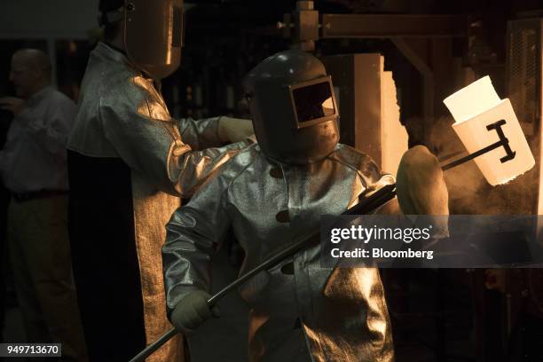 An employee pulls a crucible of molten glass from a furnace at the Corning Inc. Sullivan Park Science & Technology Center in Corning, New York, U.S.,...