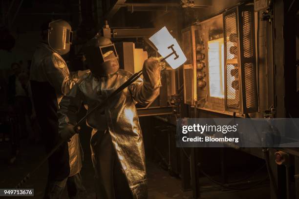 An employee pulls a crucible of molten glass from a furnace at the Corning Inc. Sullivan Park Science & Technology Center in Corning, New York, U.S.,...