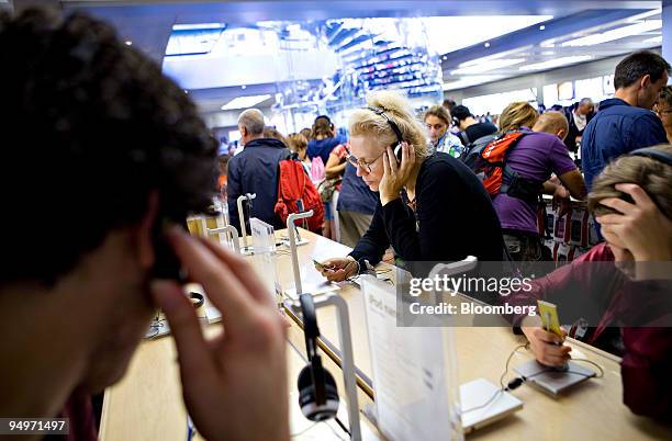 Annemiek Determann, visiting New York from Paris, center, tests out an iPod Nano inside the Apple Inc. Fifth Avenue store in New York, U.S., on...