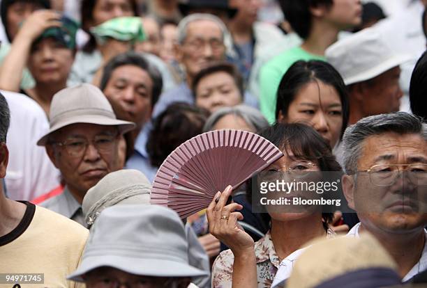 People listen to a speech by Taro Aso, Japan's prime minister and president of the Liberal Democratic Party , unseen, during a campaign rally for the...