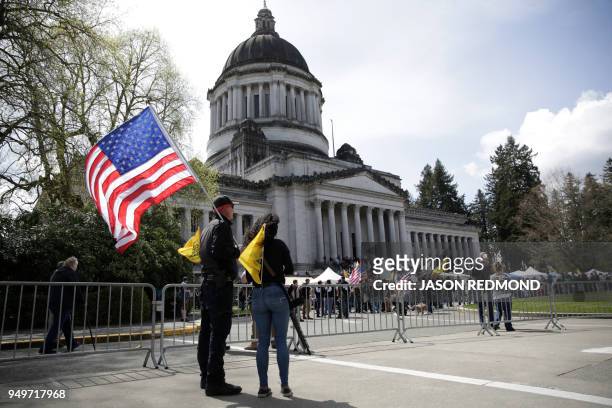 Couple is pictured with a US flag and firearm during the "March for Our Rights" pro-gun rally at the state capitol in Olympia, Washington on April...