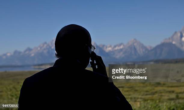 The Teton Range stands in the background as Henrique Meirelles, president of the Central Bank of Brazil, talks on a cell phone outside the Jackson...