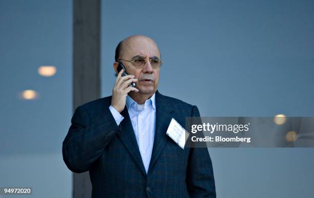 Henrique Meirelles, president of the Central Bank of Brazil, talks on a cell phone outside the Jackson Lake Lodge during a coffee break at the...