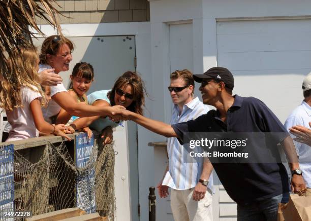 President Barack Obama, right, greets other patrons during a stop to pick up a a take-out lunch of fried seafood at Nancy's Restaurant in Oak Bluffs,...