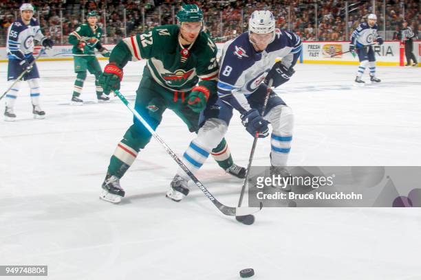 Jacob Trouba of the Winnipeg Jets and Nino Niederreiter of the Minnesota Wild skate to the puck in Game Three of the Western Conference First Round...