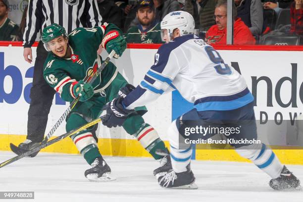 Jared Spurgeon of the Minnesota Wild passes the puck with Andrew Copp of the Winnipeg Jets defending in Game Three of the Western Conference First...