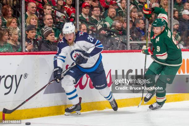 Patrik Laine of the Winnipeg Jets and Mikko Koivu of the Minnesota Wild skate to the puck in Game Three of the Western Conference First Round during...