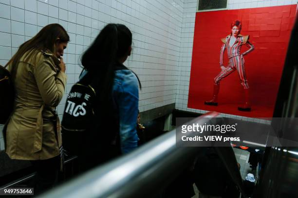 People walk at a subway station while images of David Bowie are displayed as art installations on April 20, 2018 in New York, NY. A Bowie exhibition...